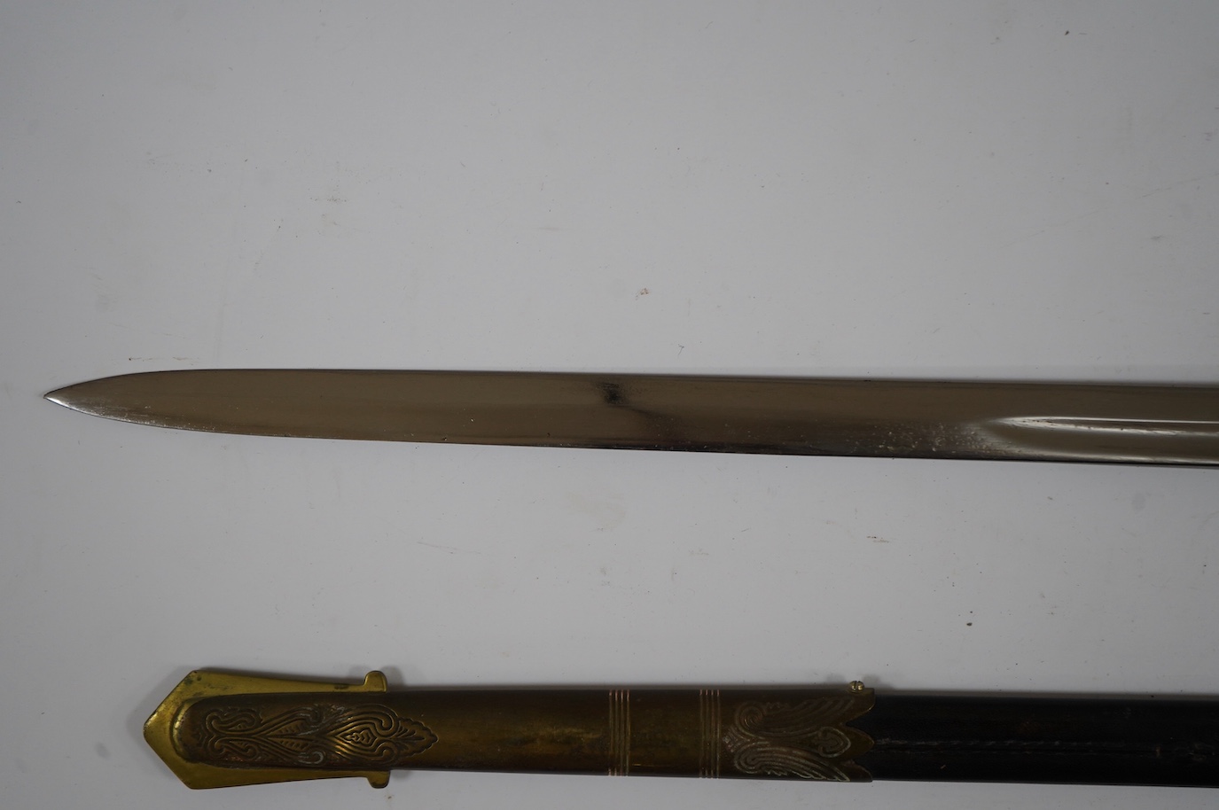 A George VI naval officer’s dress sword by Wilkinson (unnumbered), with regulation brass hilt with folding guard, engraved P.A.R. Gould R.N., bullion dress knot, in its brass mounted leather scabbard and contained in its